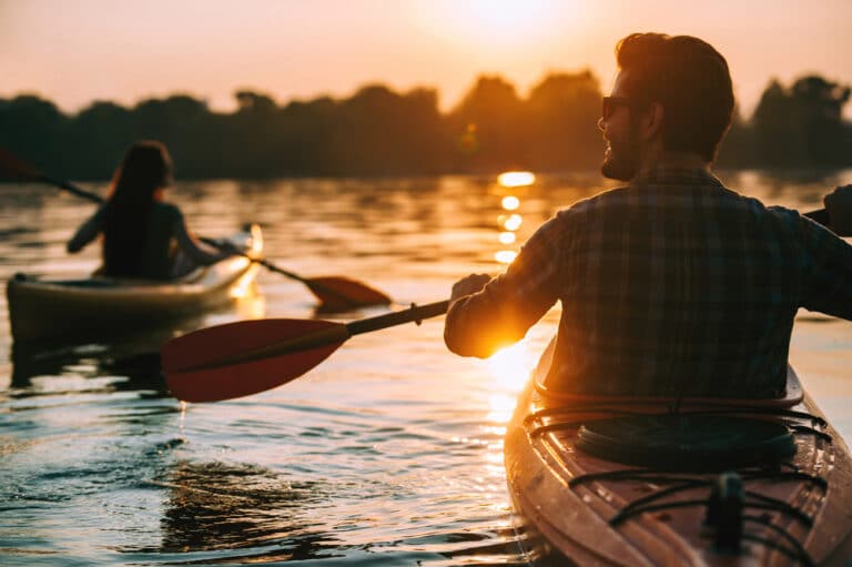 A couple enjoying a sunset kayak on waters like those at Wapsipinicon River Trail in Iowa