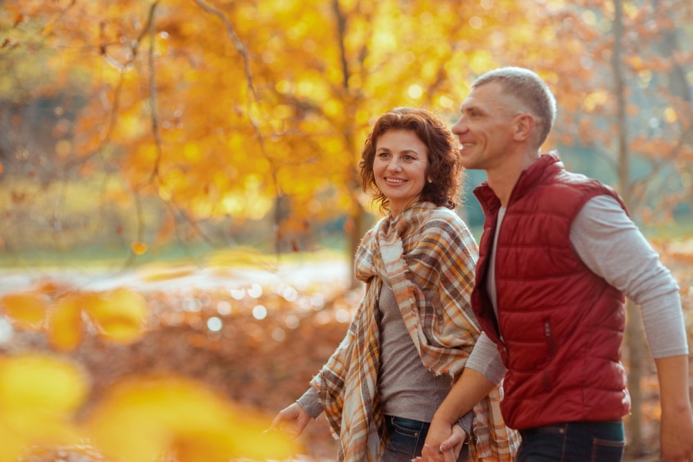 Couple enjoying a walk through fall foliage: The best Midwest vacation ideas