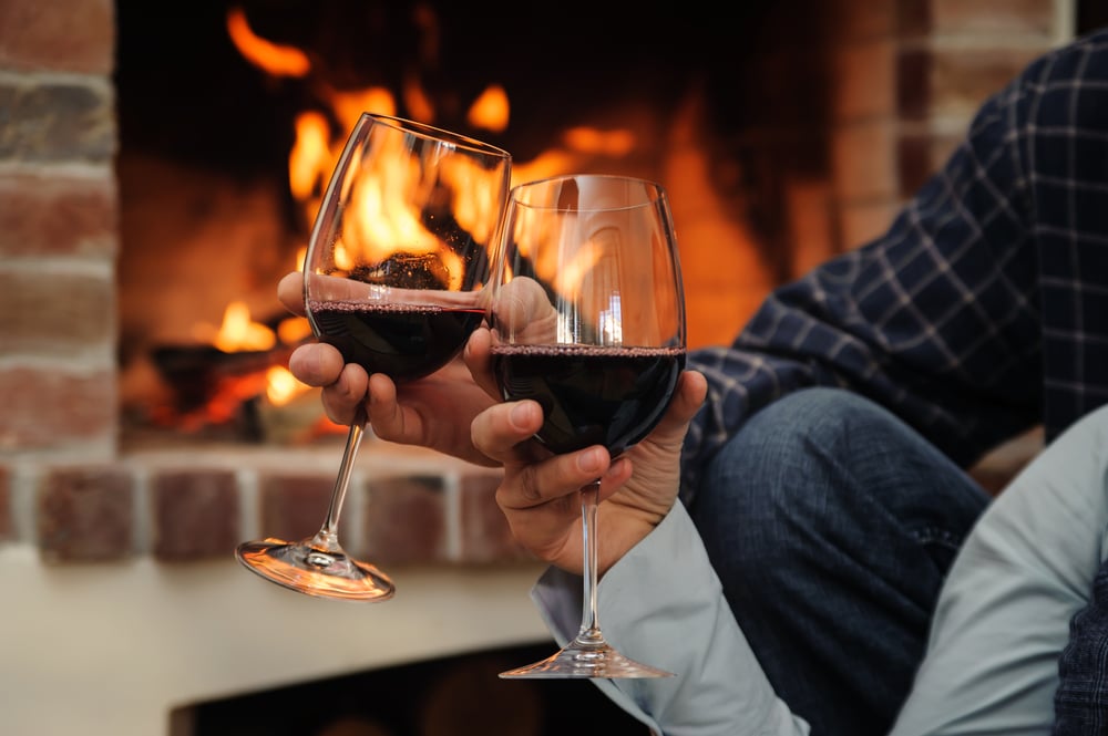 Couple enjoying glasses of wine in front of the fire during their fall getaways in the Midwest along the Great River Road