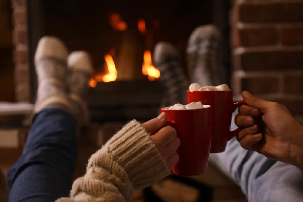 Couple enjoying hot cocoa by the fire during romantic getaways in Iowa