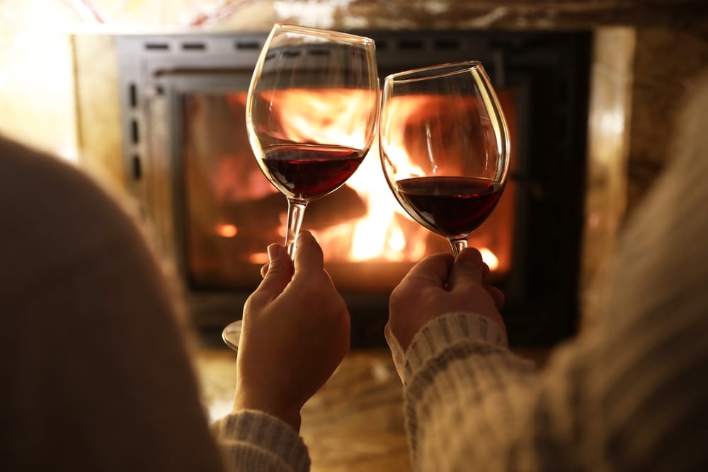 Couple warming up with a glass of wine by the fire, while enjoying Bed and Breakfasts in the best towns in Minnesota