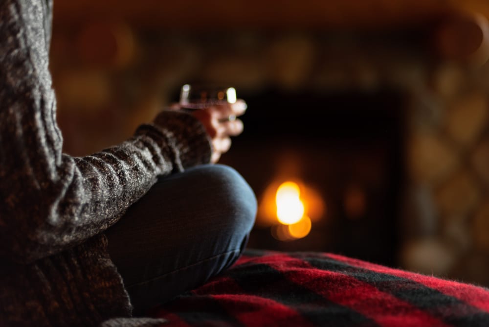 Woman sitting by the fire with wine, at one of the top-rated Bed and Breakfasts in Wisconsin near Cascade Mountain