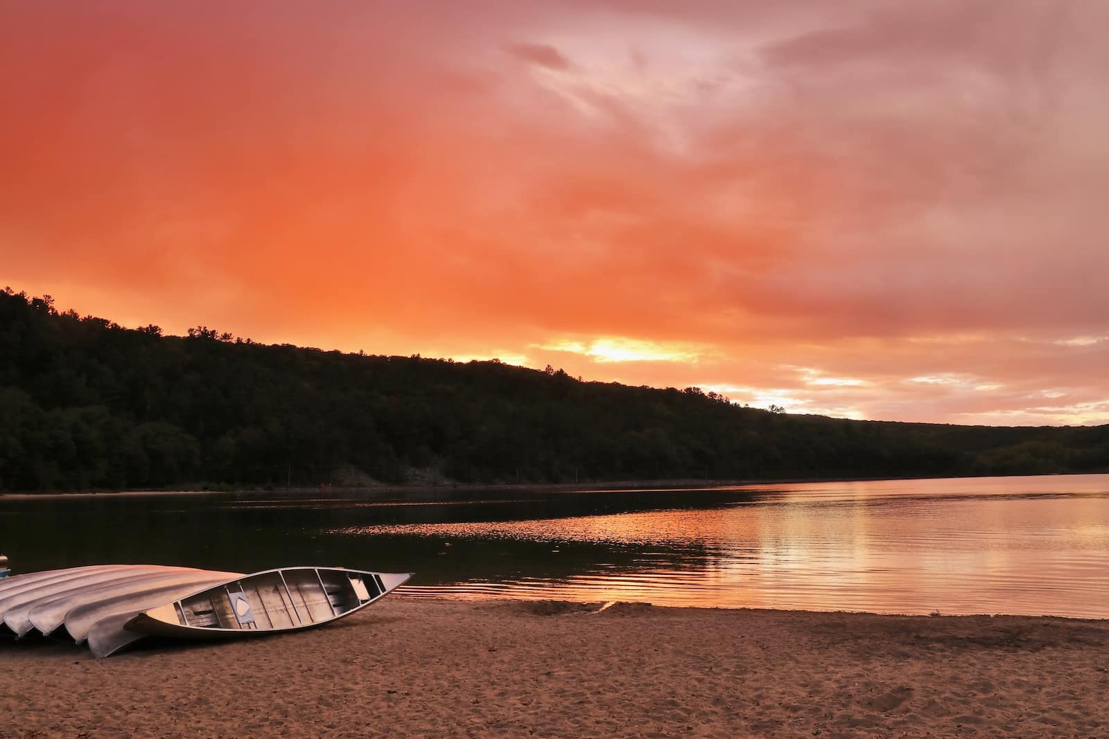 Amazing nature background. Dramatic sunset over Devils Lake with boats on the sandy beach at South shore. 